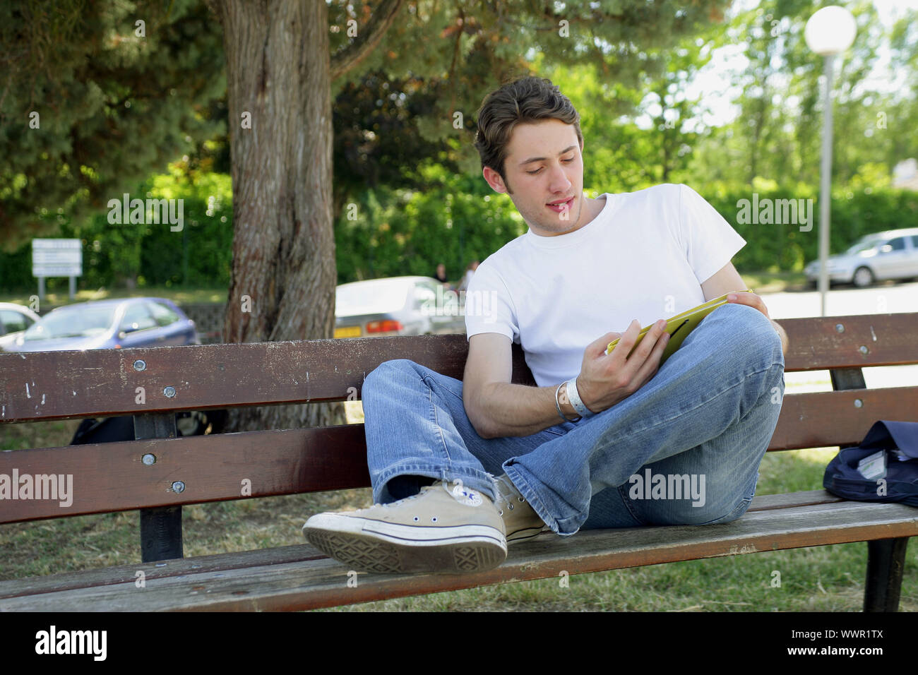 Teenager reading on a park bench Stock Photo - Alamy