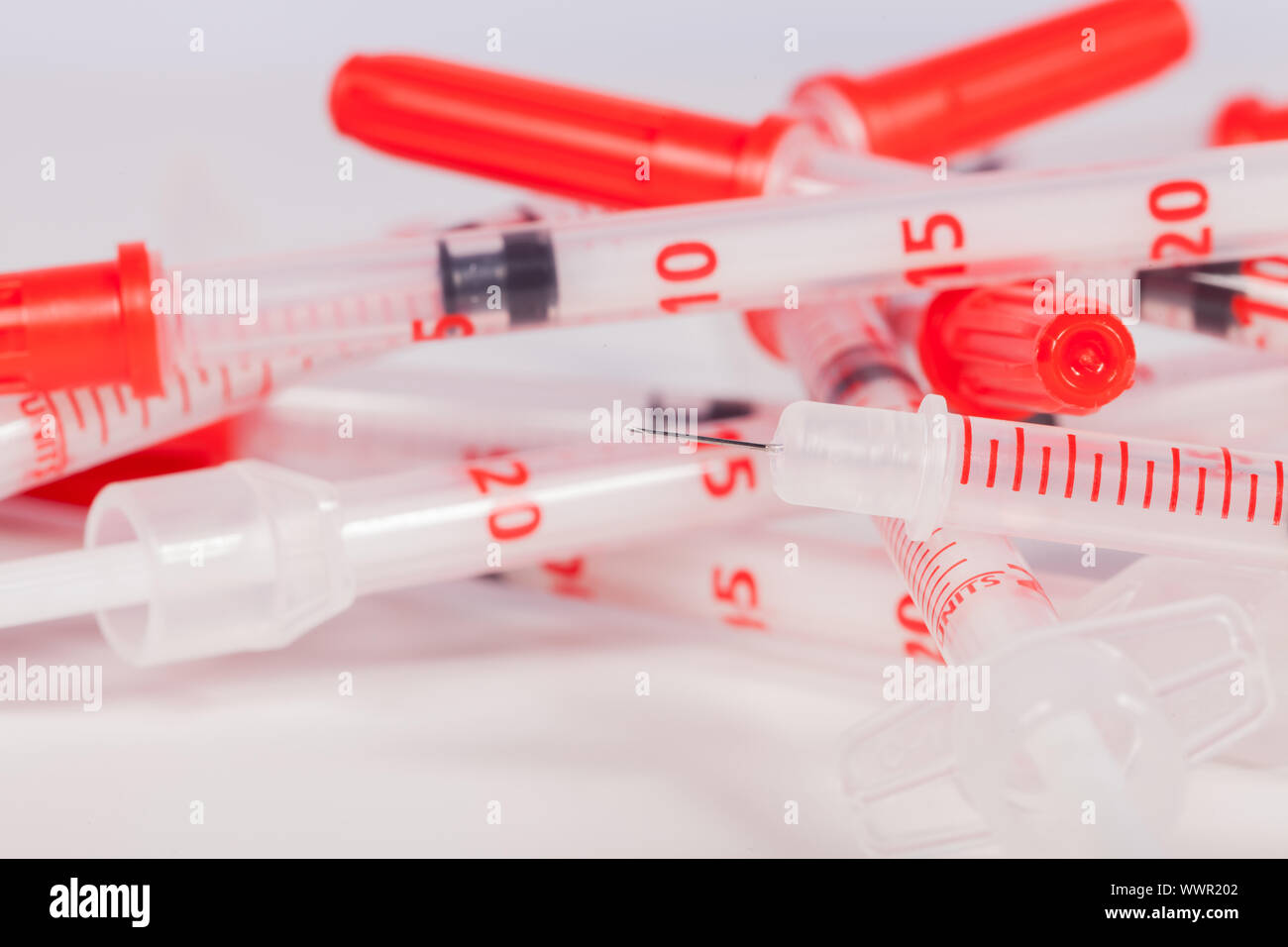 Pile of Empty Syringes with Red Safety Caps Stock Photo
