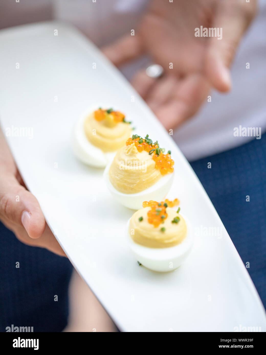 woman serving small platter with three deviled eggs Stock Photo
