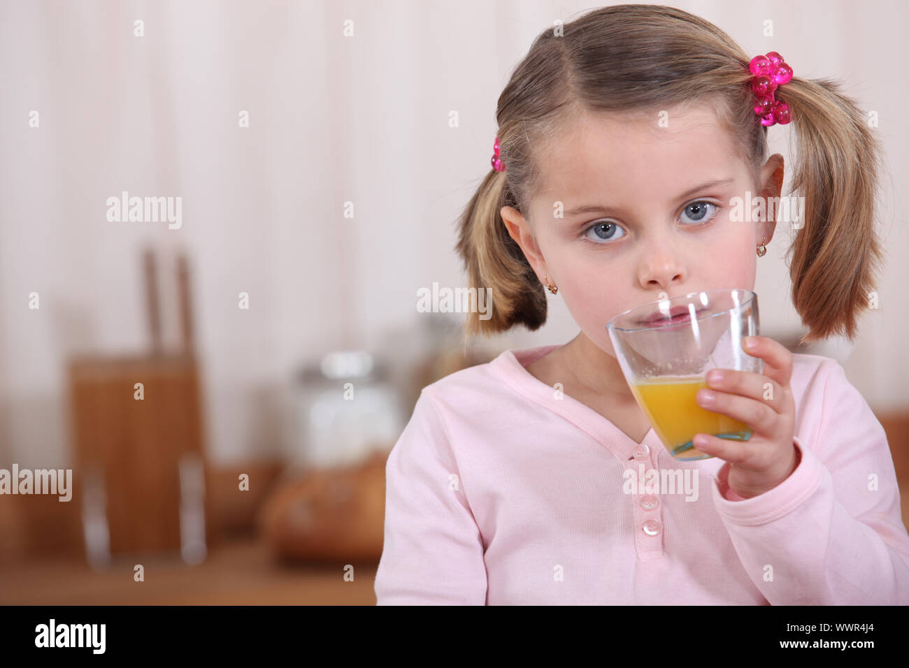 A little girl drinking orange juice in the kitchen Stock Photo Alamy
