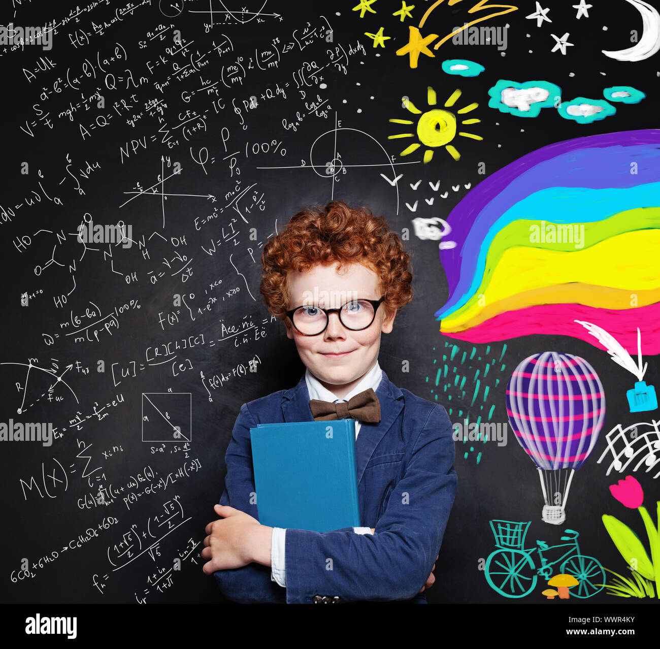 Redhead kid boy in glasses holding book with empty cover on chalkboard background with creative scetch Stock Photo
