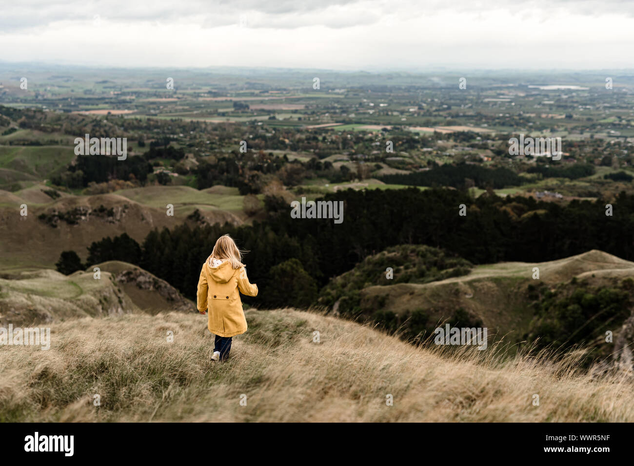 Girl in yellow jacket walking on a hilltop Stock Photo - Alamy
