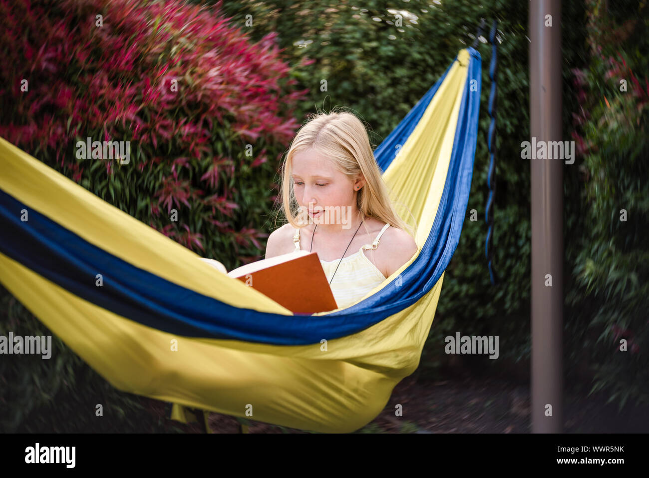 Preteen girl in hammock with a book Stock Photo