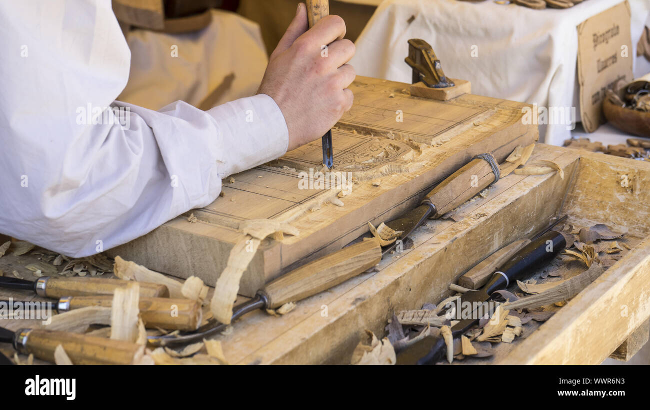 Furniture, craftsman carving wood in a medieval fair, carpentry tools Stock Photo