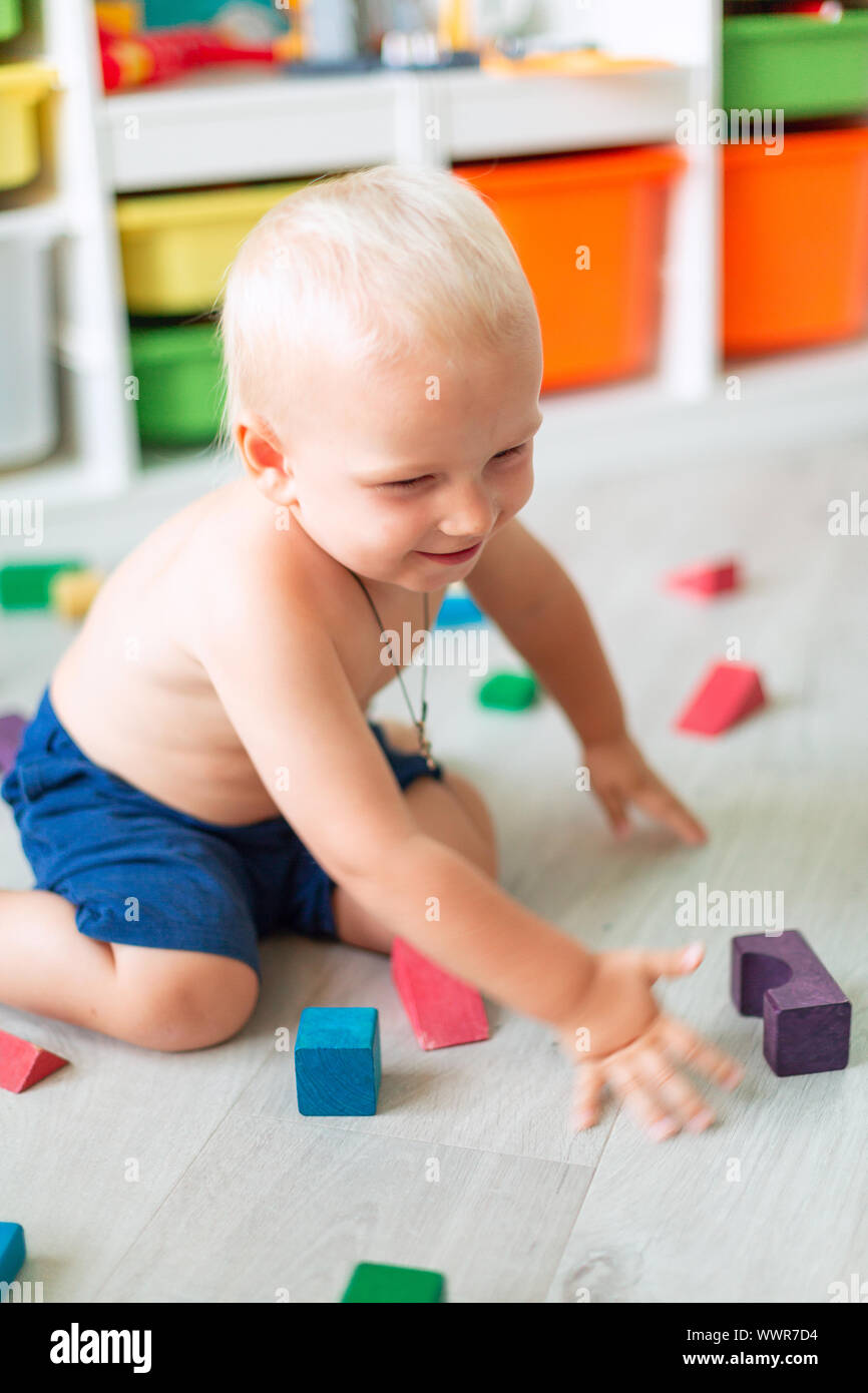 Cute baby boy playing with building blocks in kid's room Stock Photo