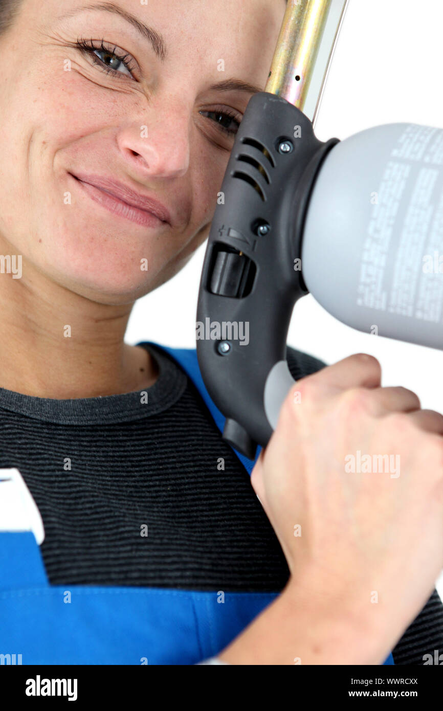 closeup portrait of young blonde female apprentice holding spot welder Stock Photo