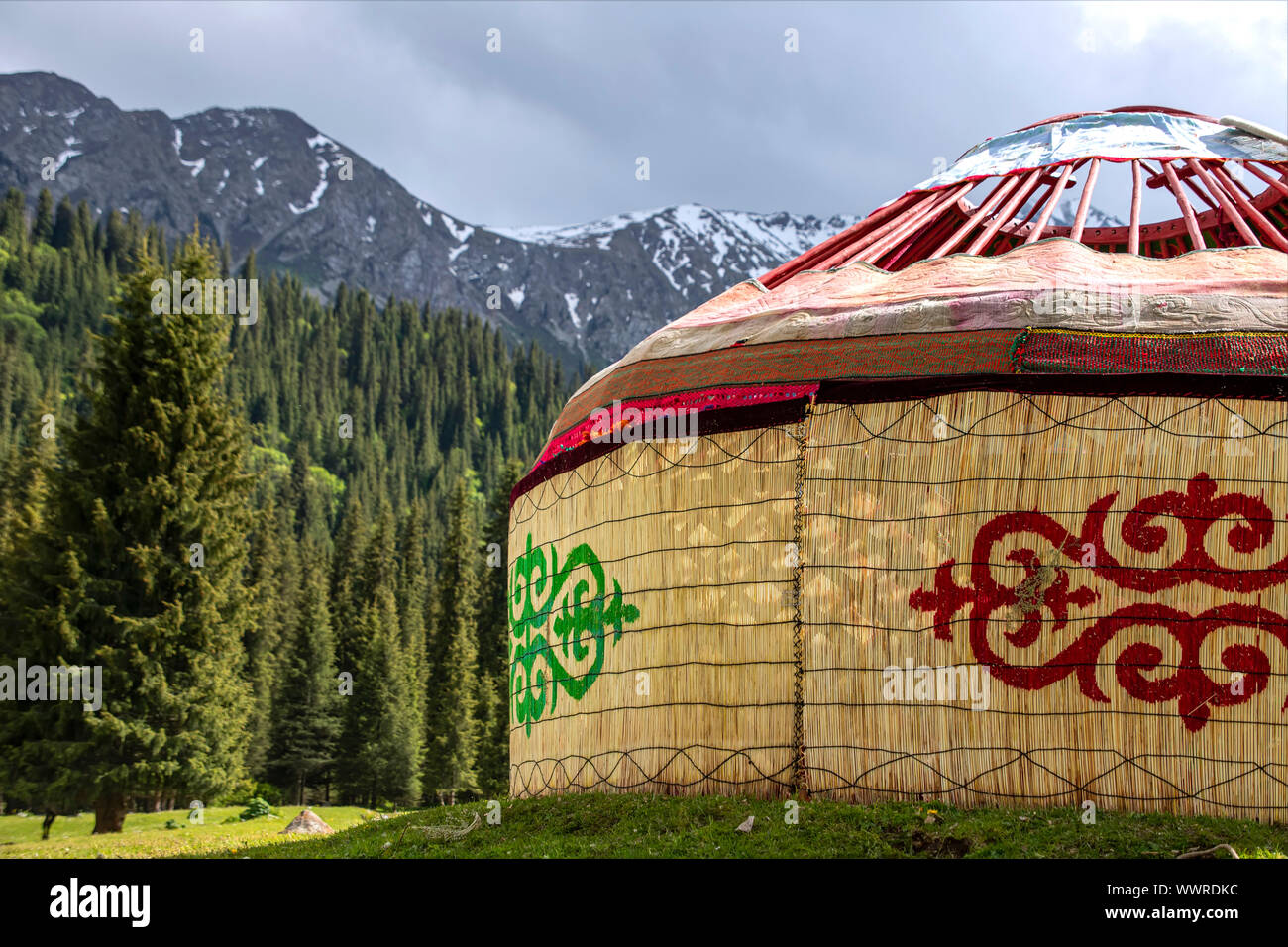 Almost ready-made Kyrgyz traditional yurt house on the background of mountains covered with coniferous forest. Kyrgyzstan Stock Photo