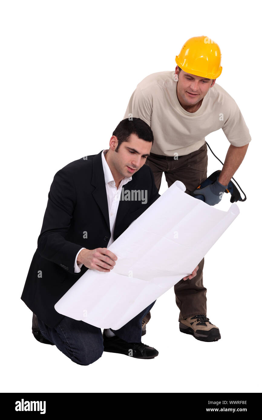 Construction worker consulting with an engineer over a drawing Stock Photo