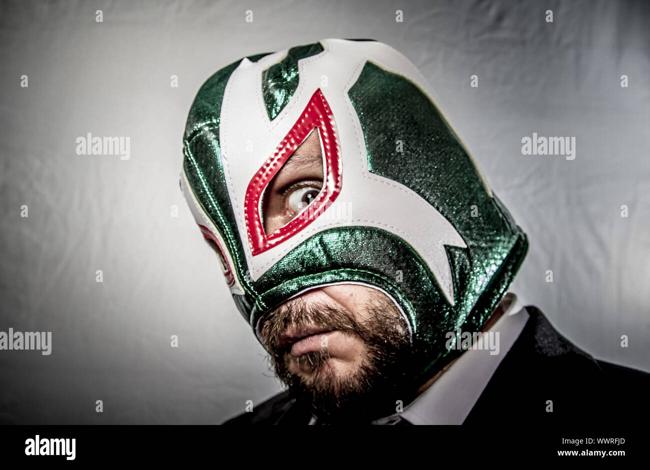 Angry businessman with mask of Mexican fighter, dressed in suit and tie Stock Photo