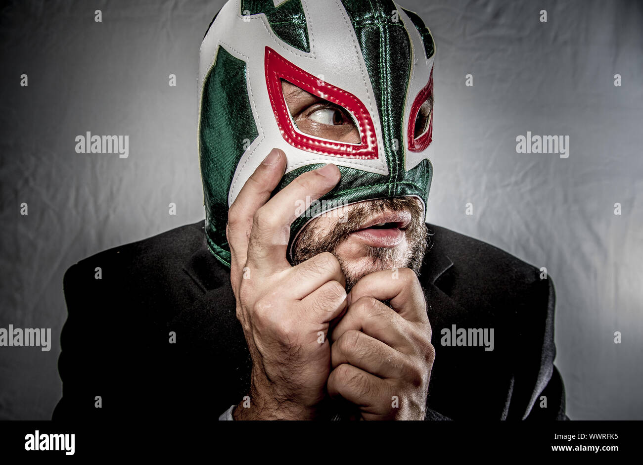 Angry businessman with mask of Mexican fighter, dressed in suit and tie Stock Photo