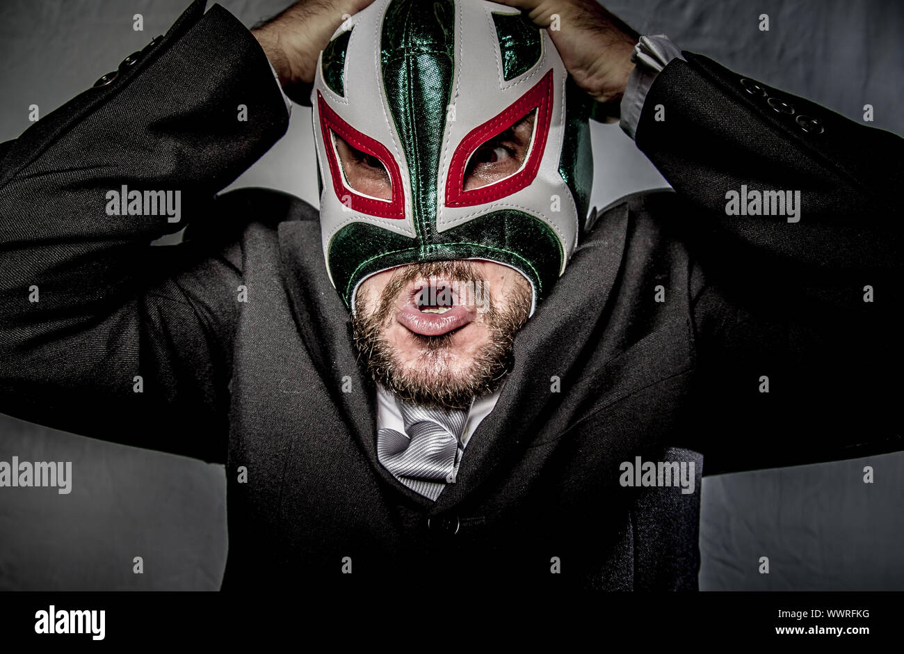 Angry businessman with mask of Mexican fighter, dressed in suit and tie Stock Photo