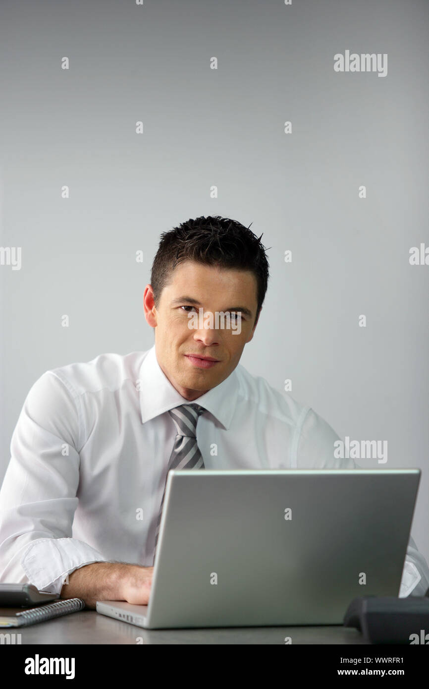 Young salesman sat at desk Stock Photo
