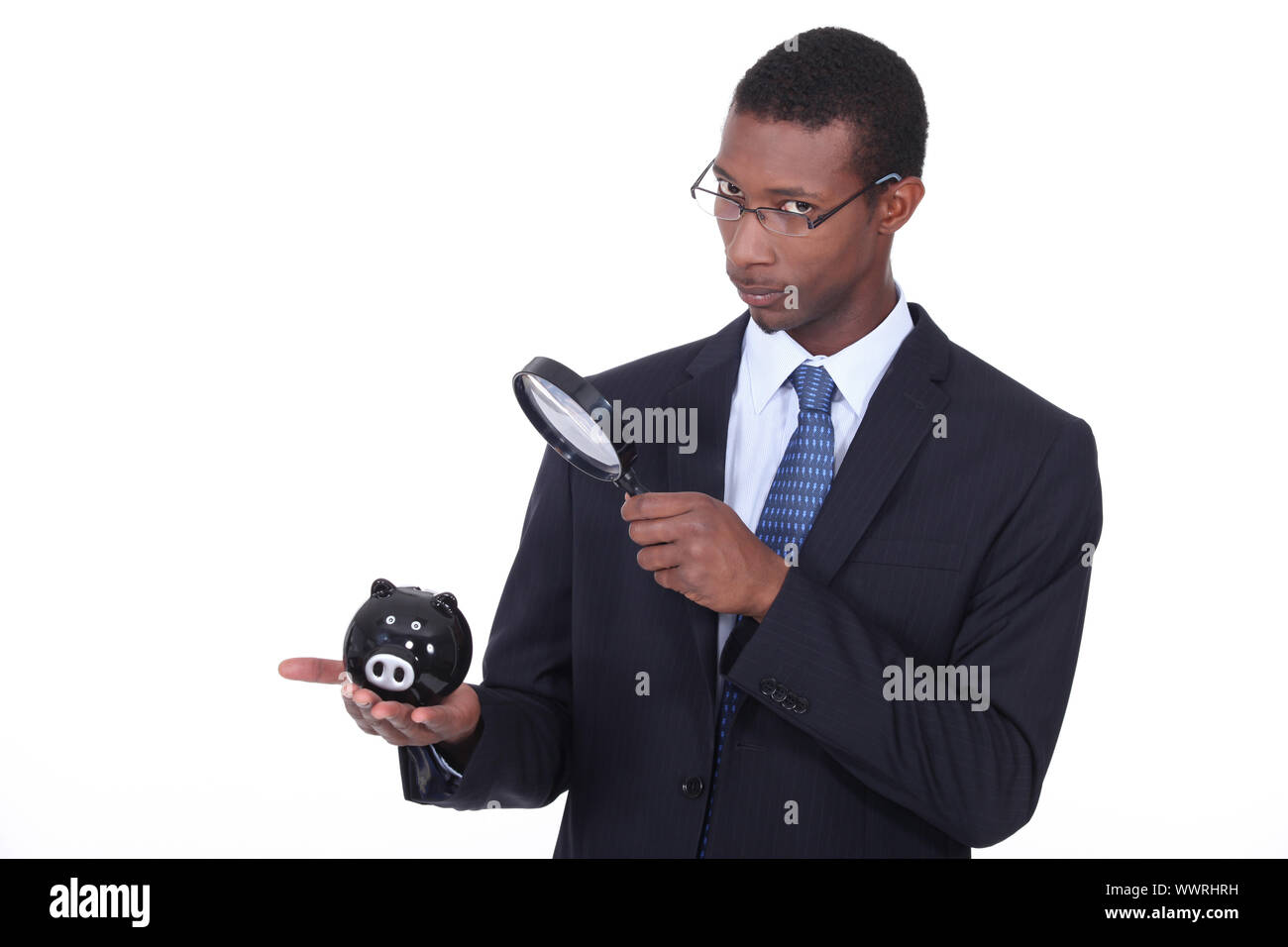 African man looking at a piggy bank through a magnifying glass Stock ...