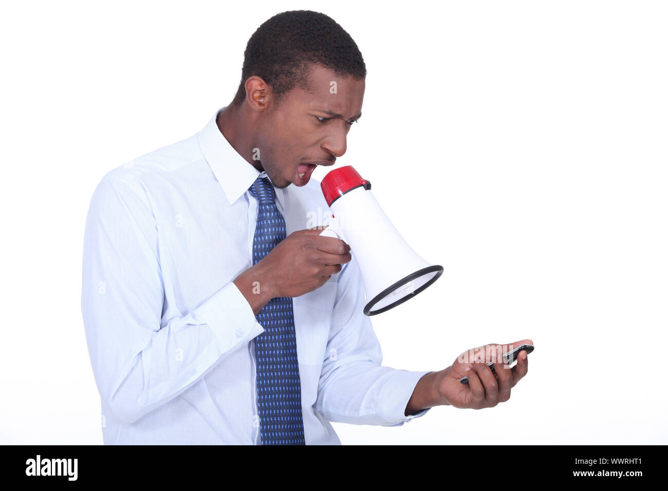 Man shouting through a megaphone at a cellphone Stock Photo