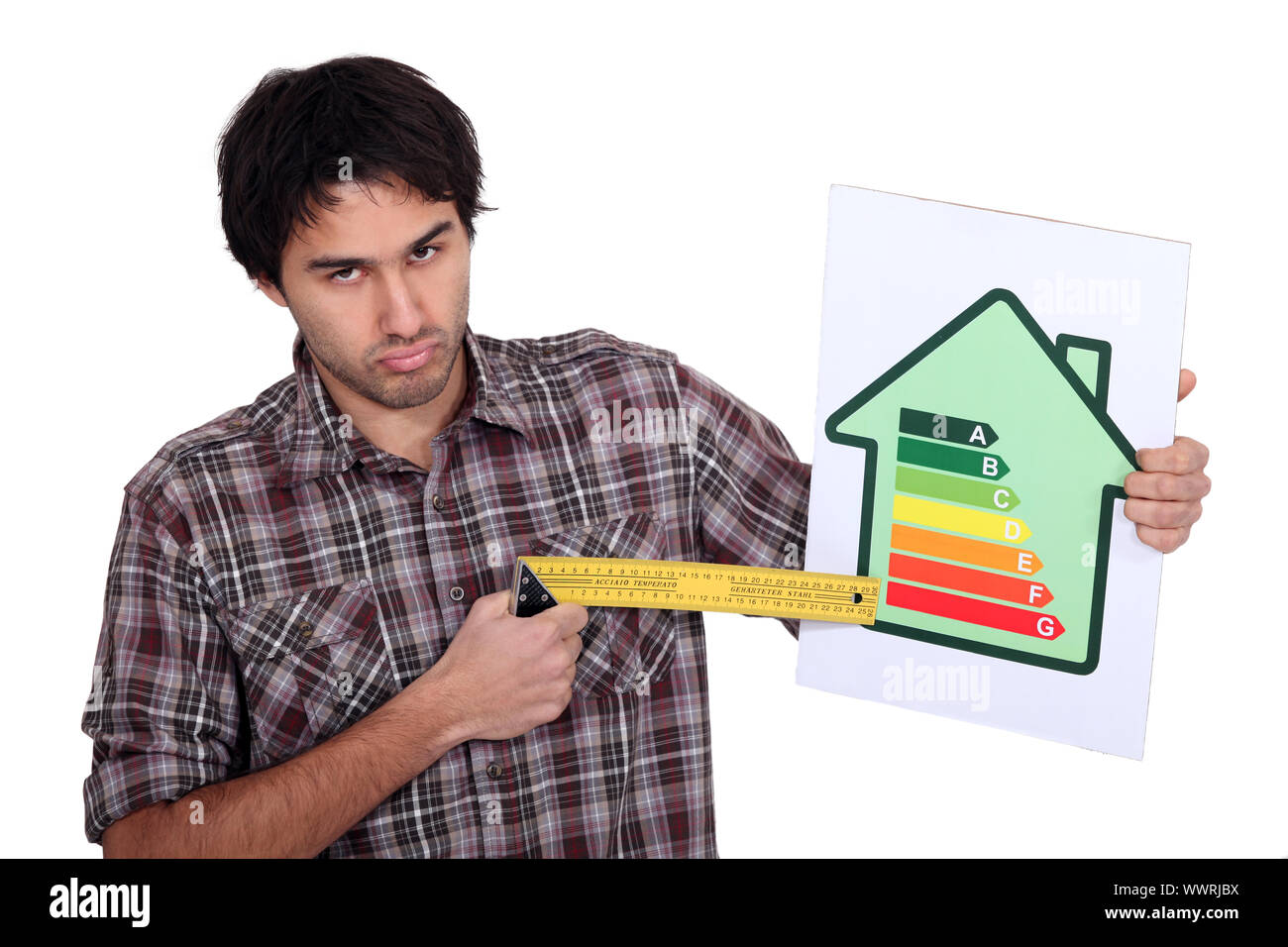 Grumpy man pointing to the lower end of an energy efficiency rating scale with a try square Stock Photo