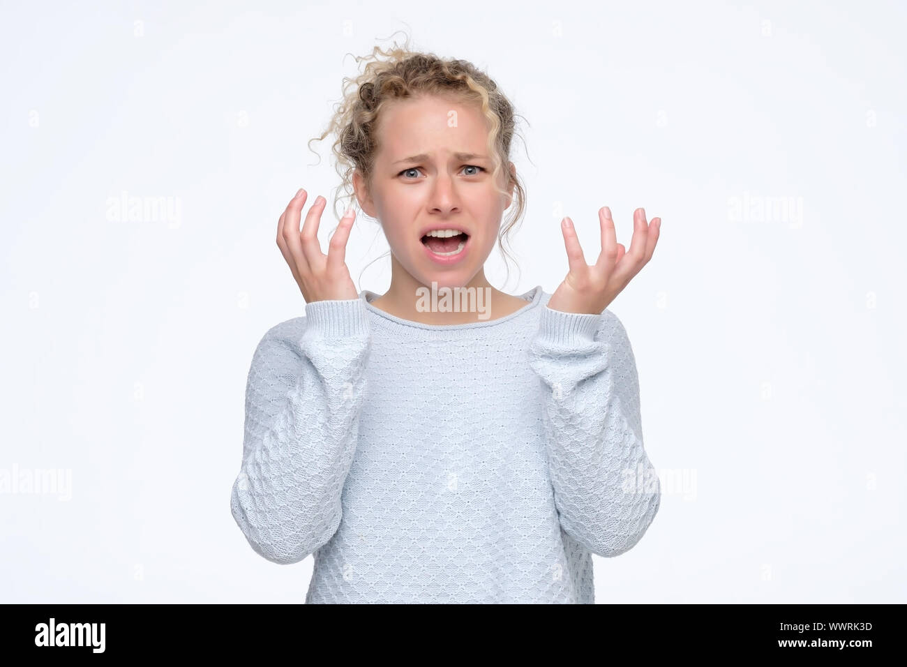 Pretty young blonde girl feeling angry and irritated. Studio shot. Negative facial human emotion Stock Photo