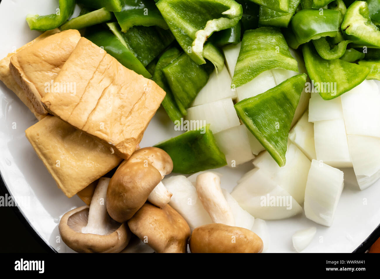 Green peppers, tofu, onion, and mushrooms in plate Stock Photo