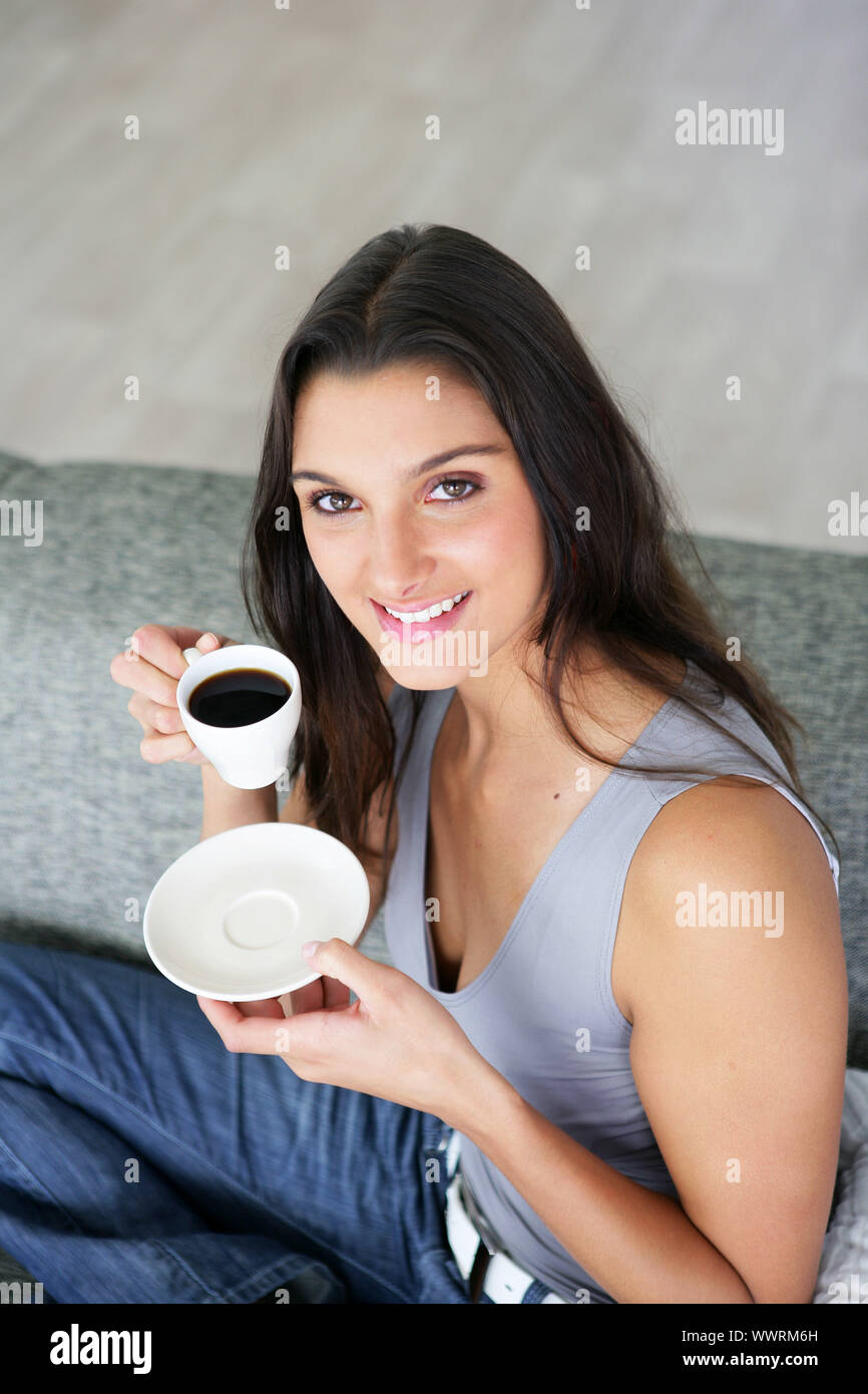 Woman sitting on a sofa with a cup of coffee Stock Photo - Alamy