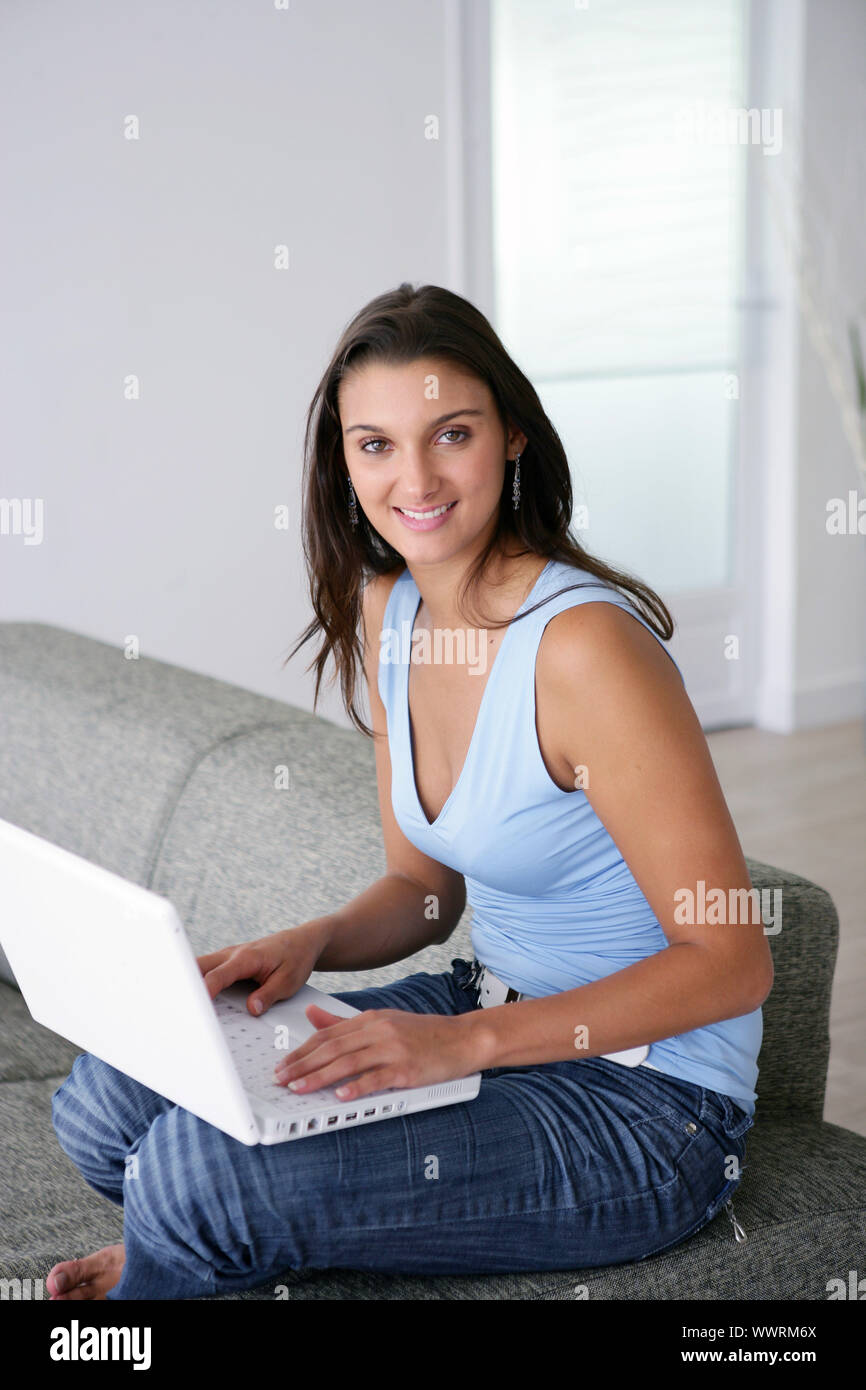 Young woman using a laptop computer on a sofa Stock Photo - Alamy