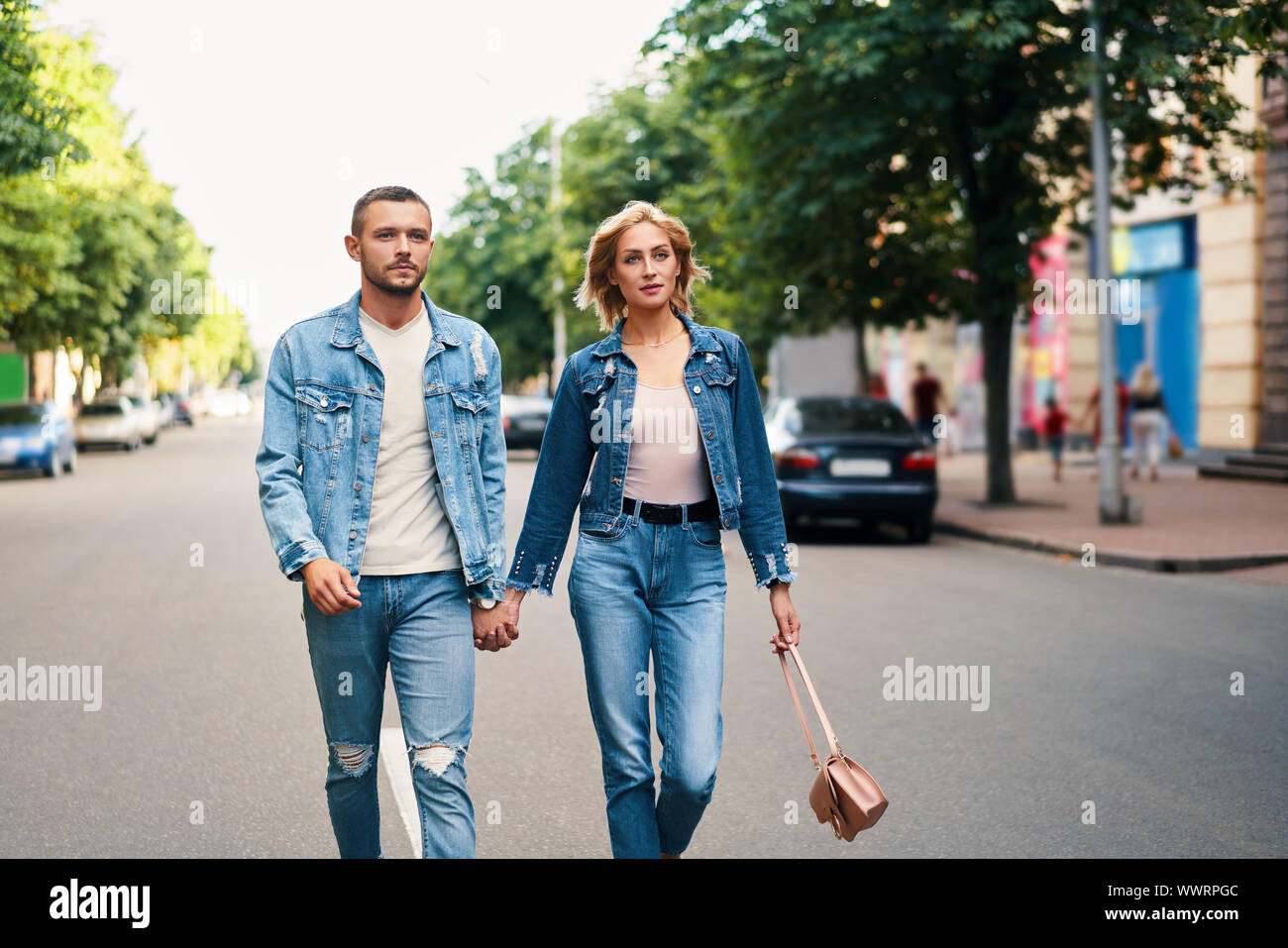 Beautiful young couple holding hands and smiling while walking outdoors. Love, dating concept Stock Photo