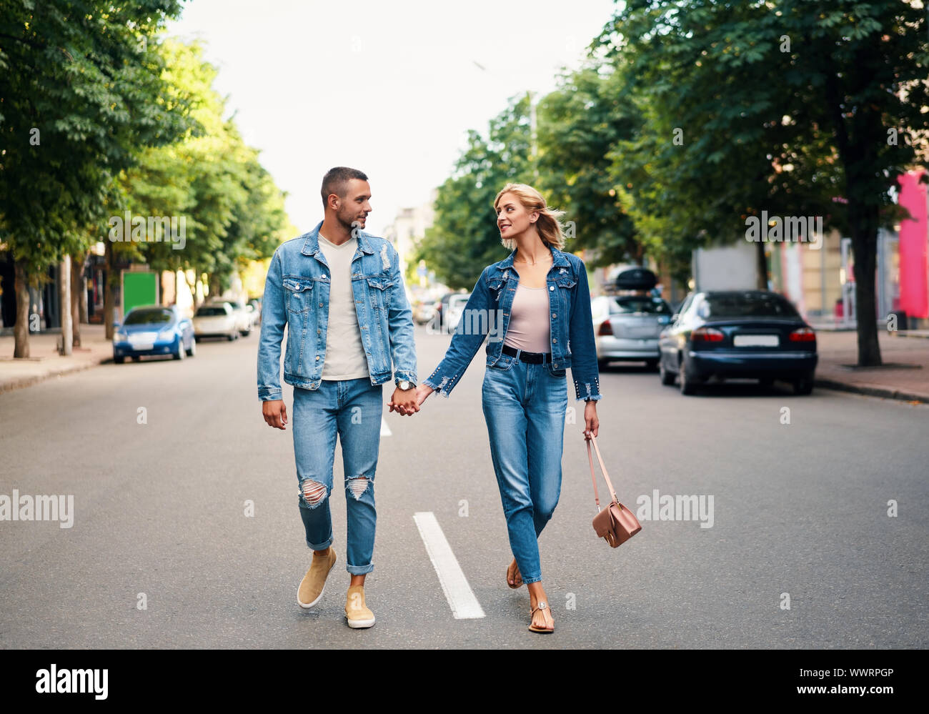 Beautiful young couple holding hands and smiling while walking outdoors. Love, dating concept Stock Photo