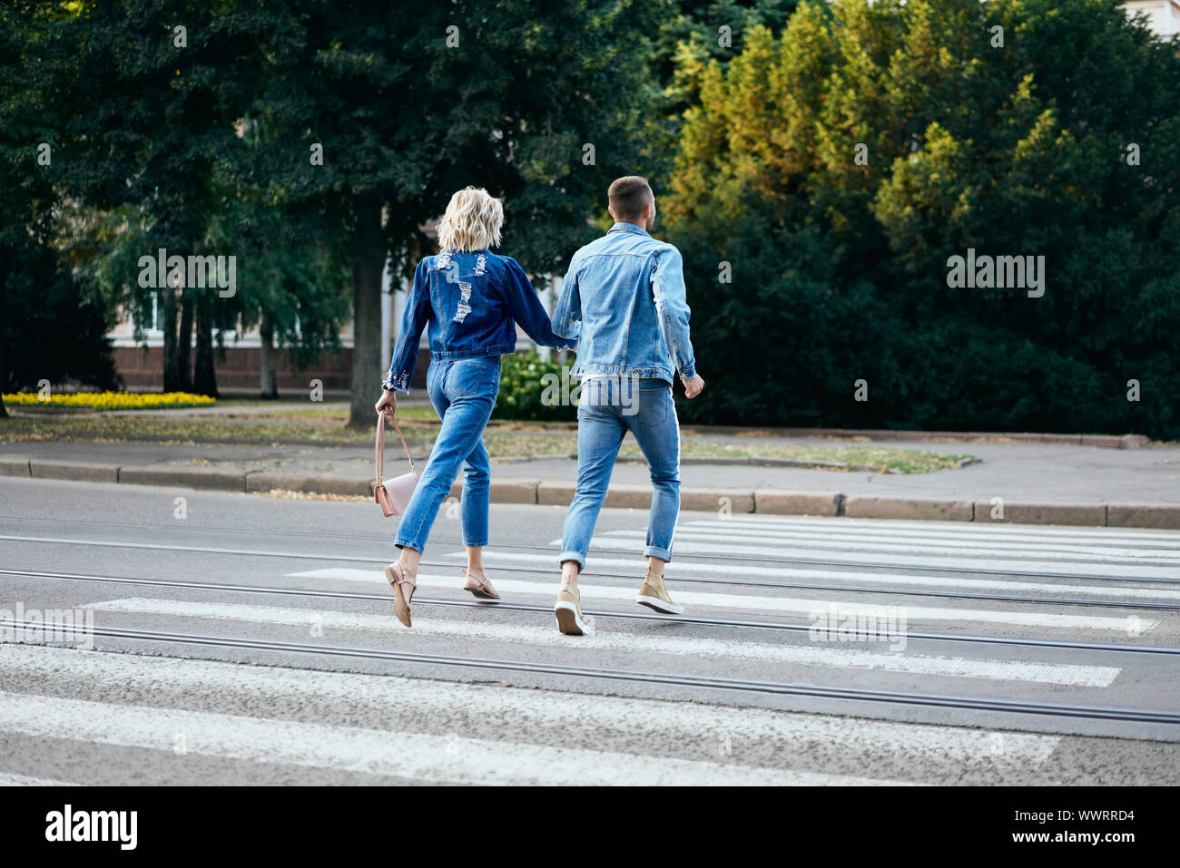 Back view of young happy couple running crosswalk in the street. Fun, walking, dating concept Stock Photo