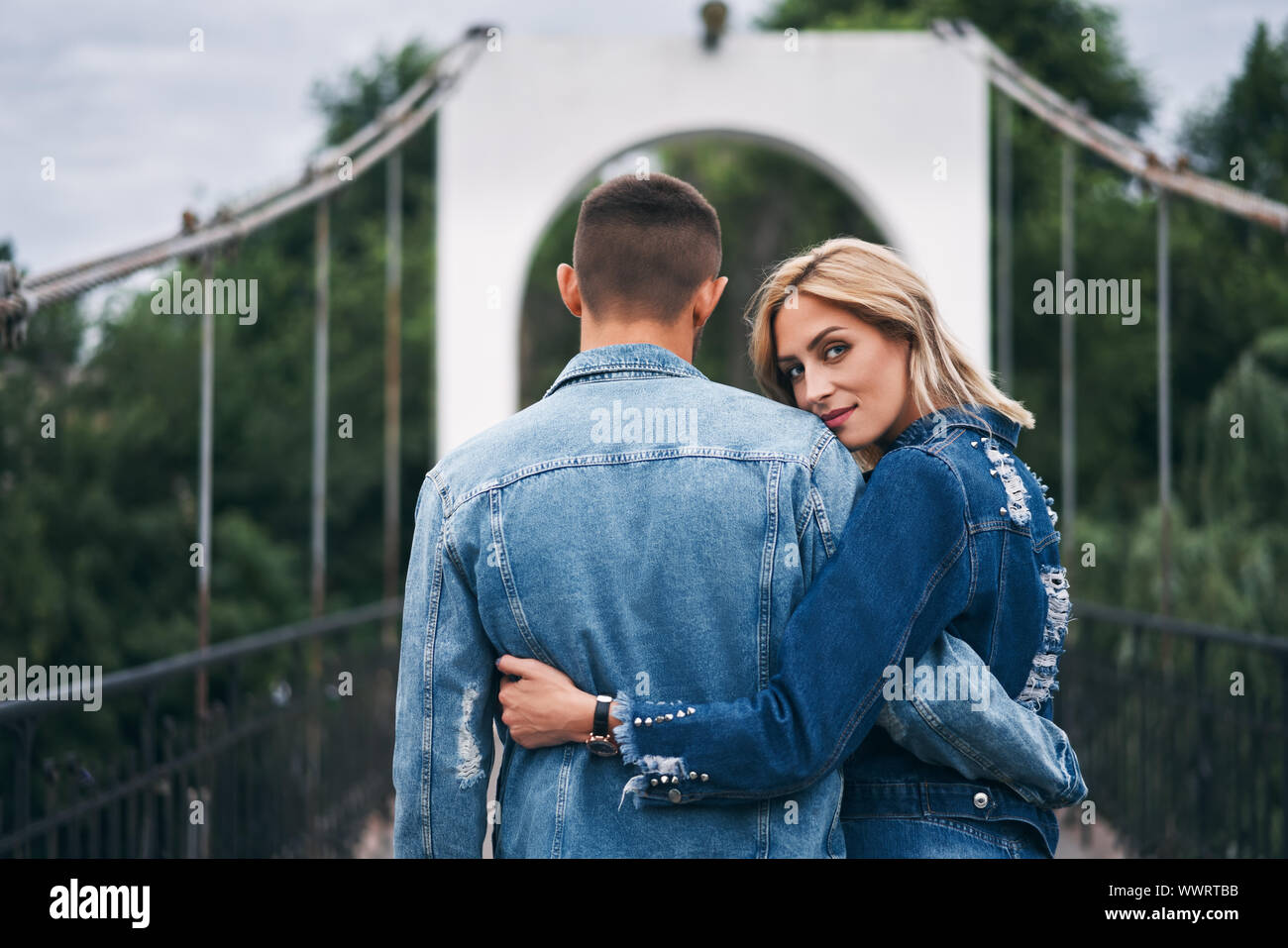 Young beautiful woman hugging her boyfriend with love outdoors. Caucasian couple in park. Tenderness, trust, happy relationship concept Stock Photo