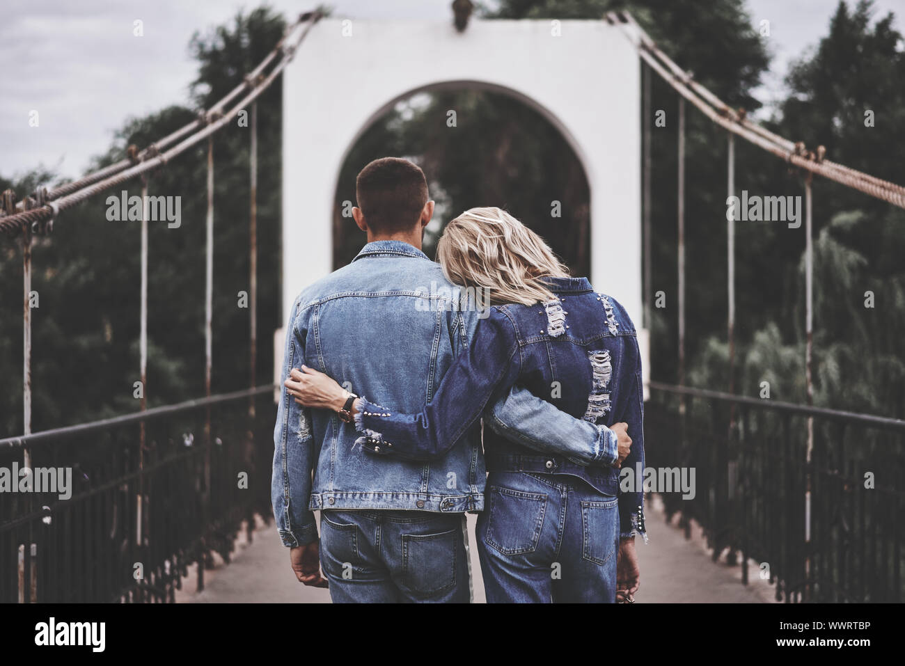 Back view of hugging couple staying on the bridge and enjoying rest. instagram filter effect Stock Photo