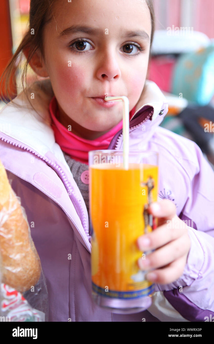 Little girl drinking juice using a straw Stock Photo