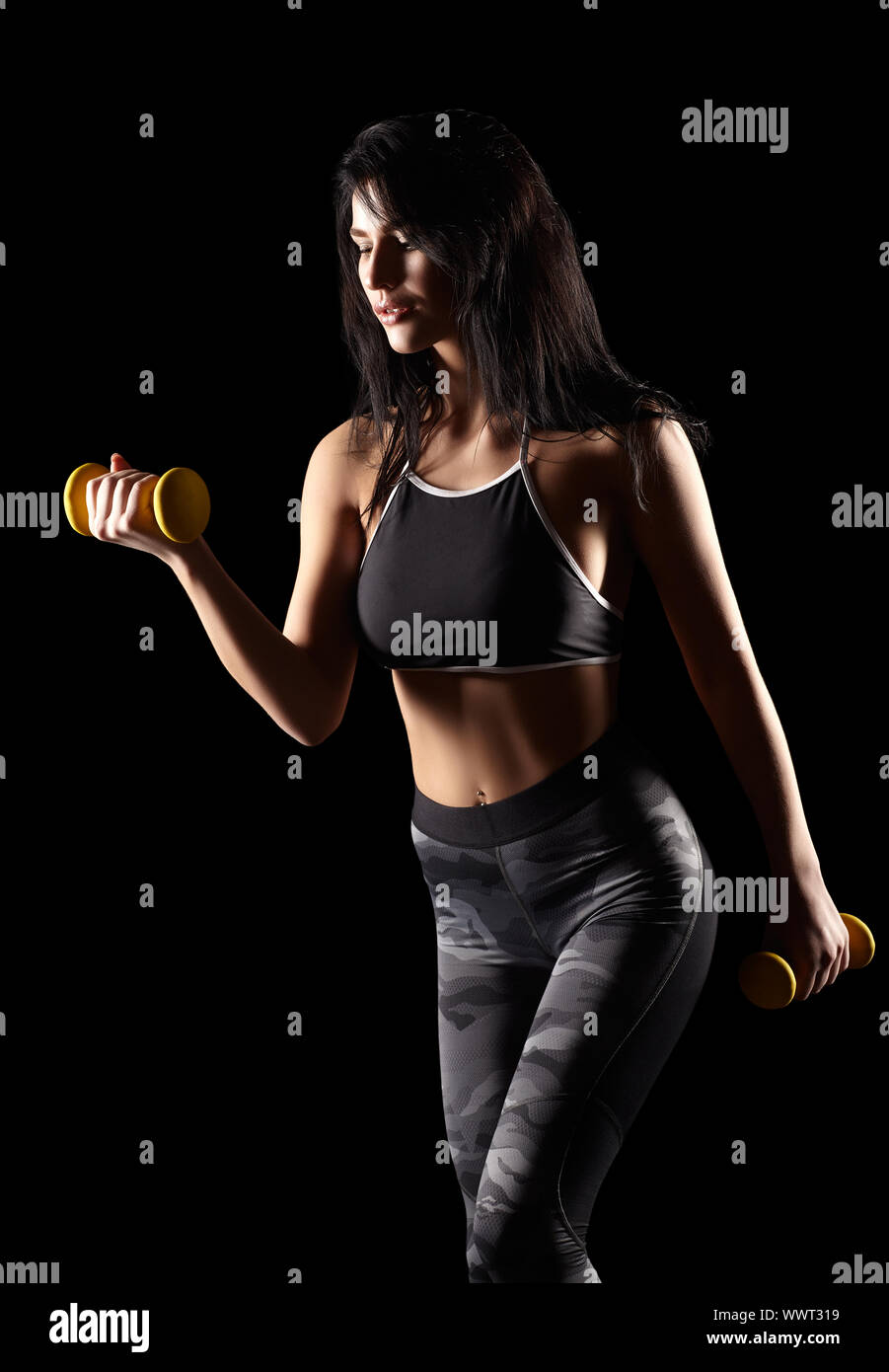 Portrait of a young brunette sporty fitness woman with dumbbell in hand Stock Photo