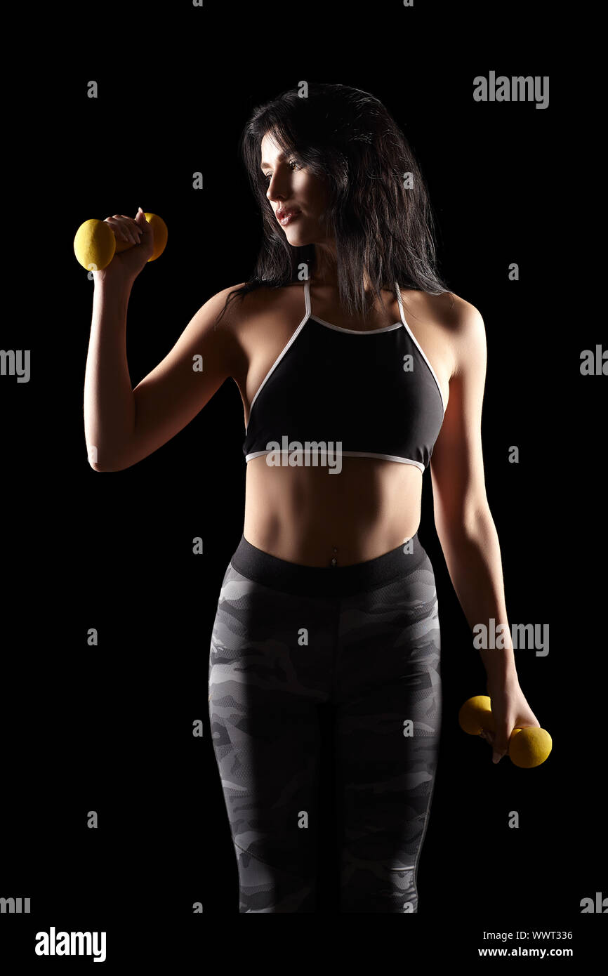 Portrait of a young brunette sporty fitness woman with dumbbell in hand Stock Photo