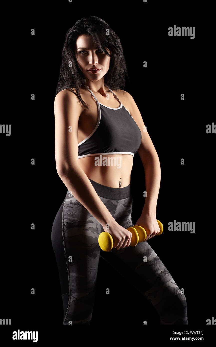 Portrait of a young brunette sporty fitness woman with dumbbell in hand Stock Photo