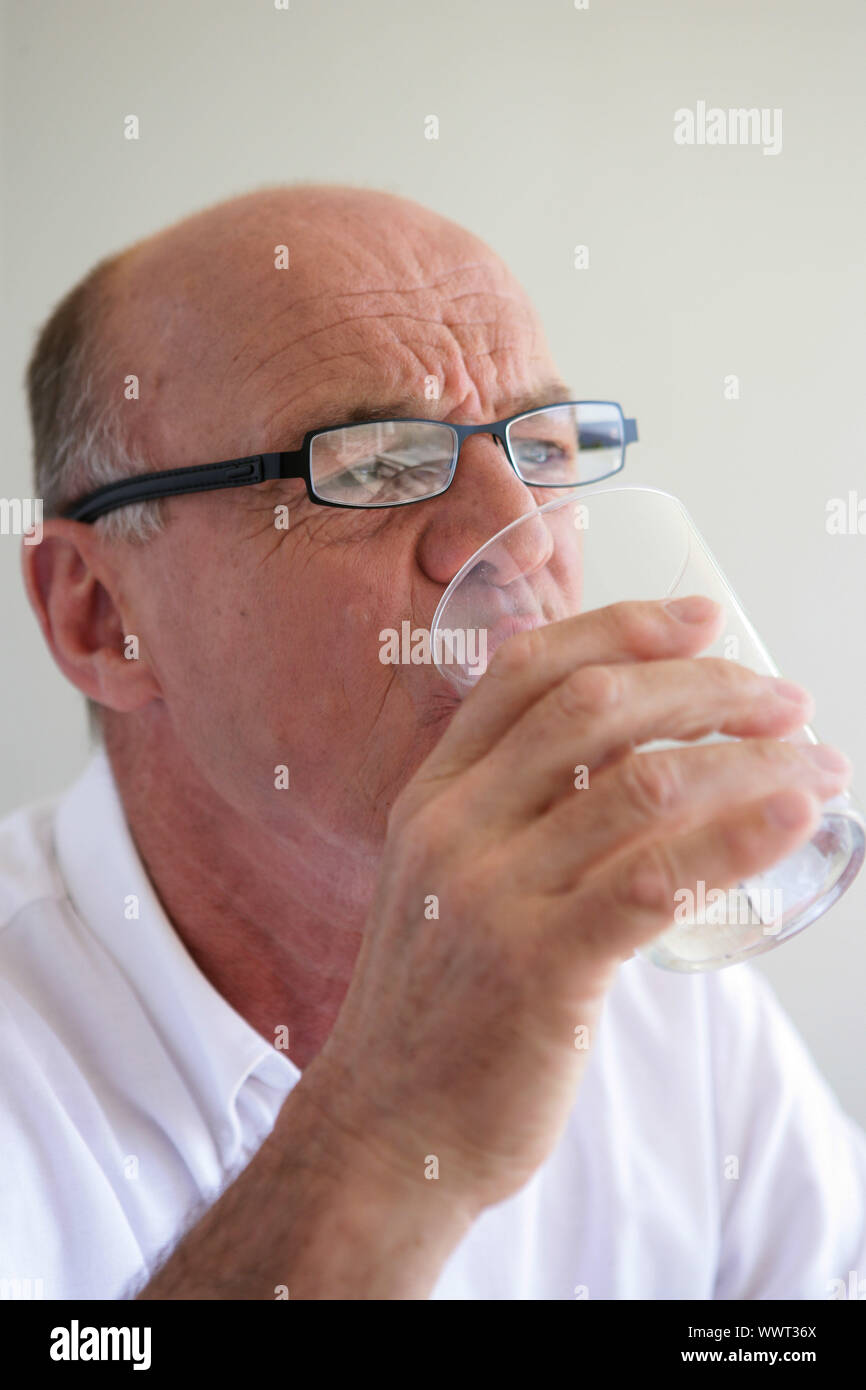 Elderly man drinking a glass of water Stock Photo