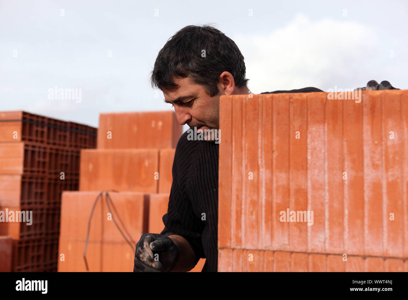 Housebuilder surrounded by large bricks Stock Photo - Alamy