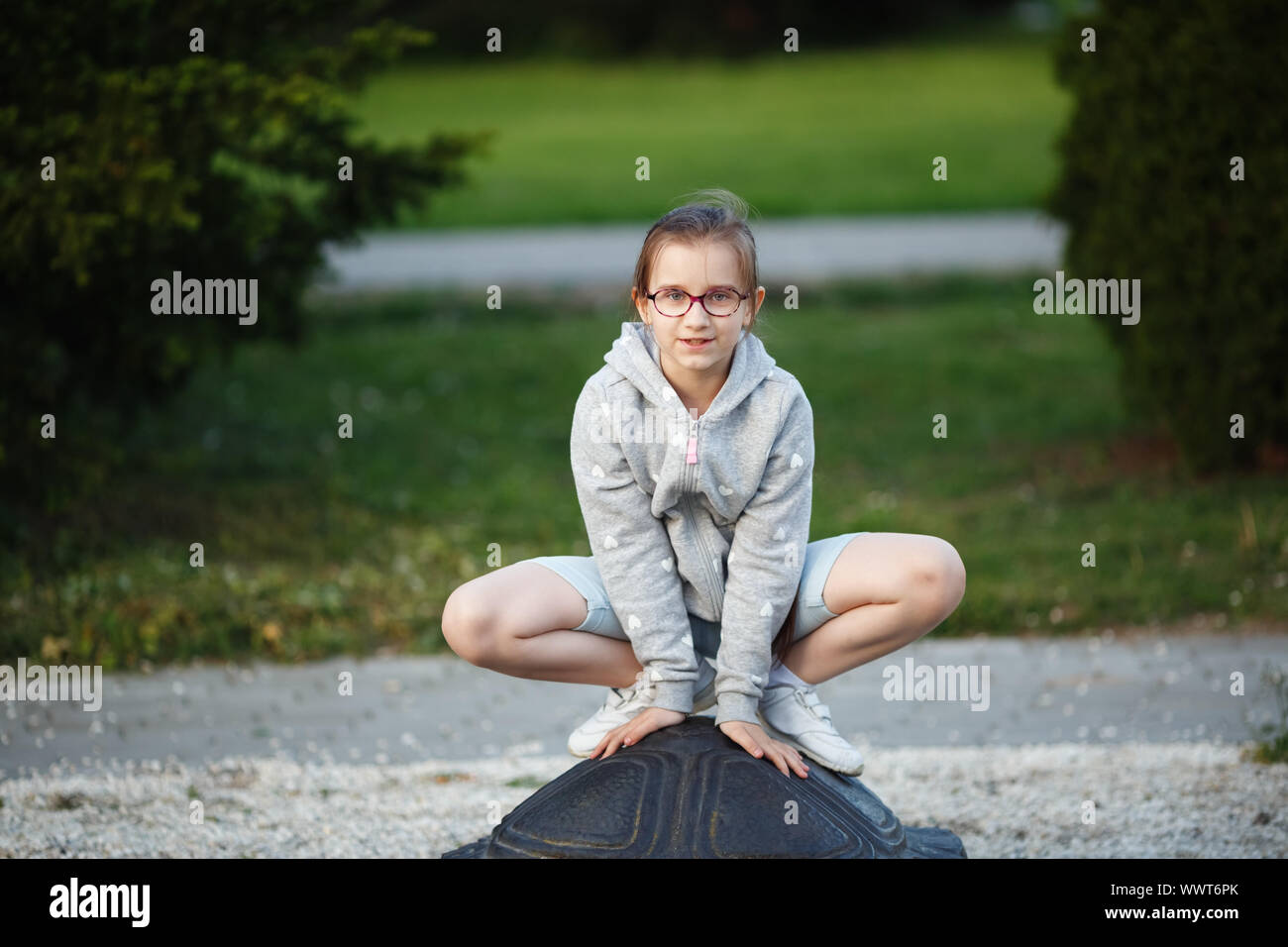 Girl child posing in a frog pose in the park. Child on the playground. Selective focus. Stock Photo
