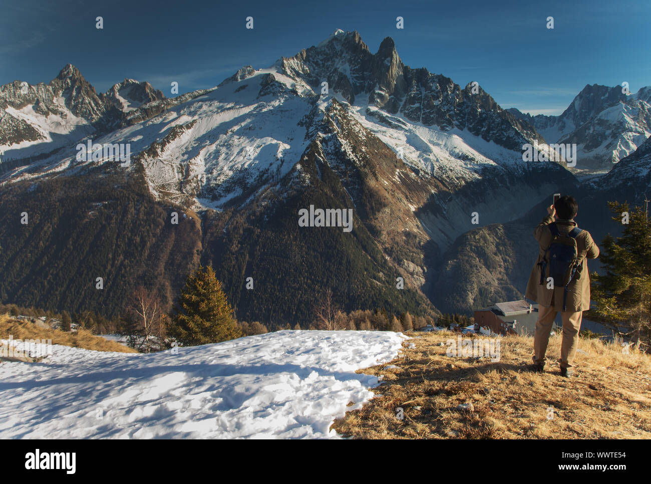 Man taking photo of alps on mobile phone Stock Photo