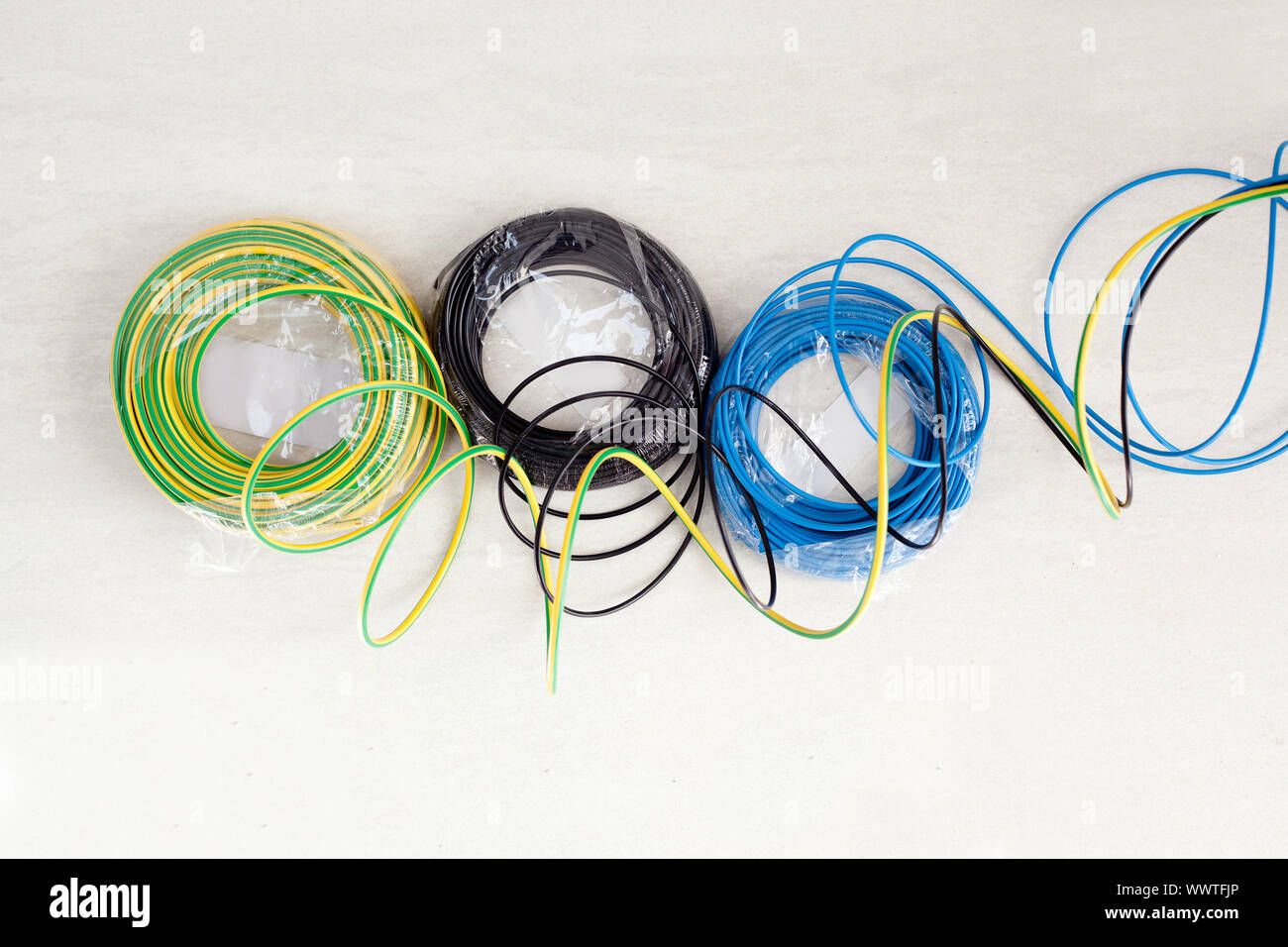 Electric cable coil in three colors black blue and green yellow earth