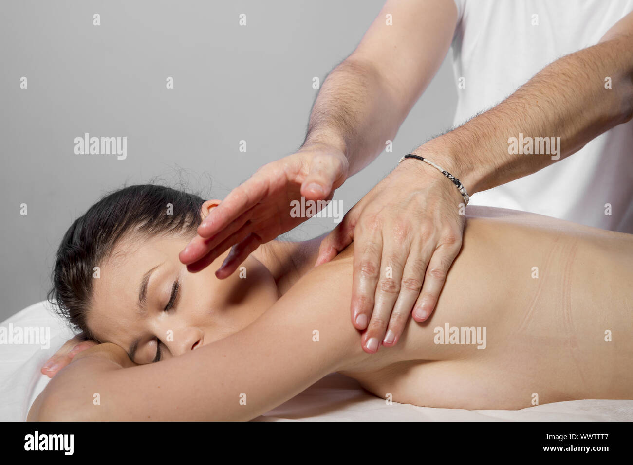Hands and relaxation, beautiful brunette woman relaxing on a stretcher receiving a therapeutic massage from hands of a professio Stock Photo