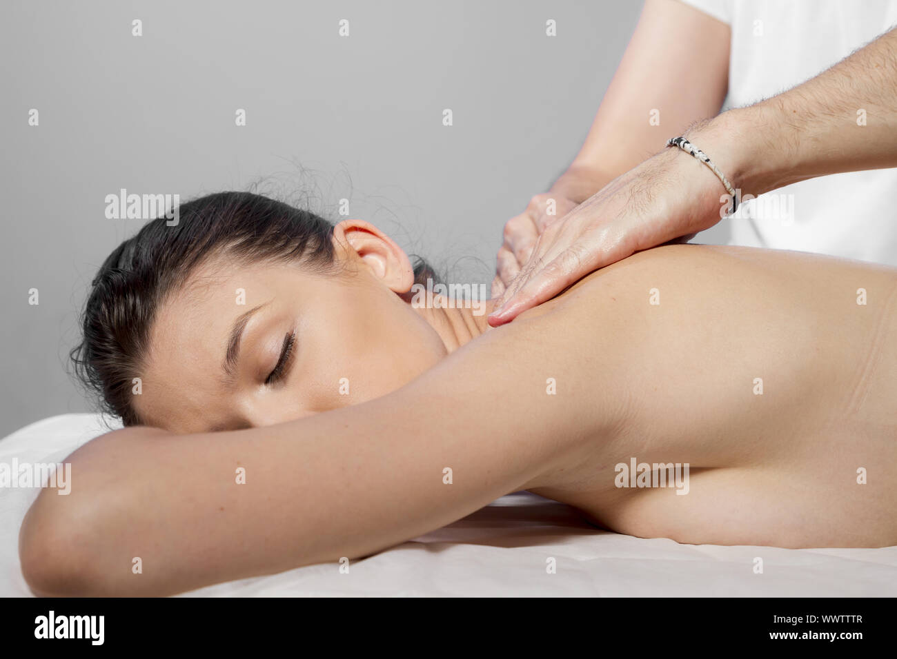 Massage and relaxation, beautiful brunette woman relaxing on a stretcher receiving a therapeutic massage from hands of a profess Stock Photo