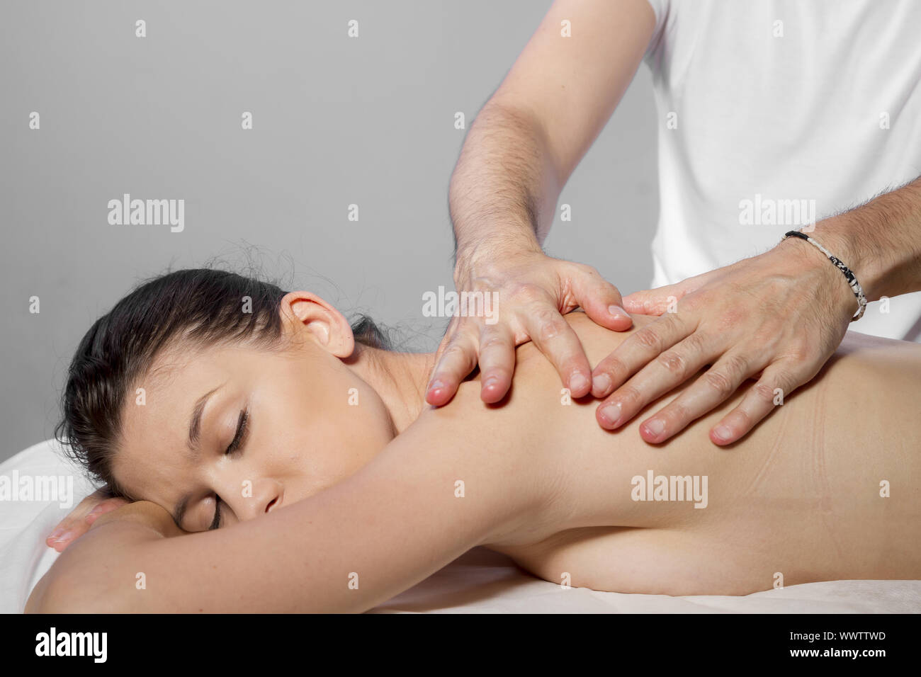 Healthy and relaxation, beautiful brunette woman relaxing on a stretcher receiving a therapeutic massage from hands of a profess Stock Photo