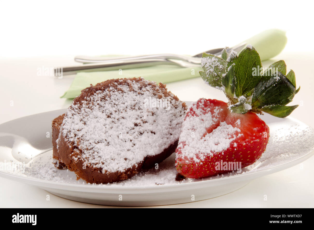 chocolate sponge roll with icing sugar and a half strawberry Stock Photo