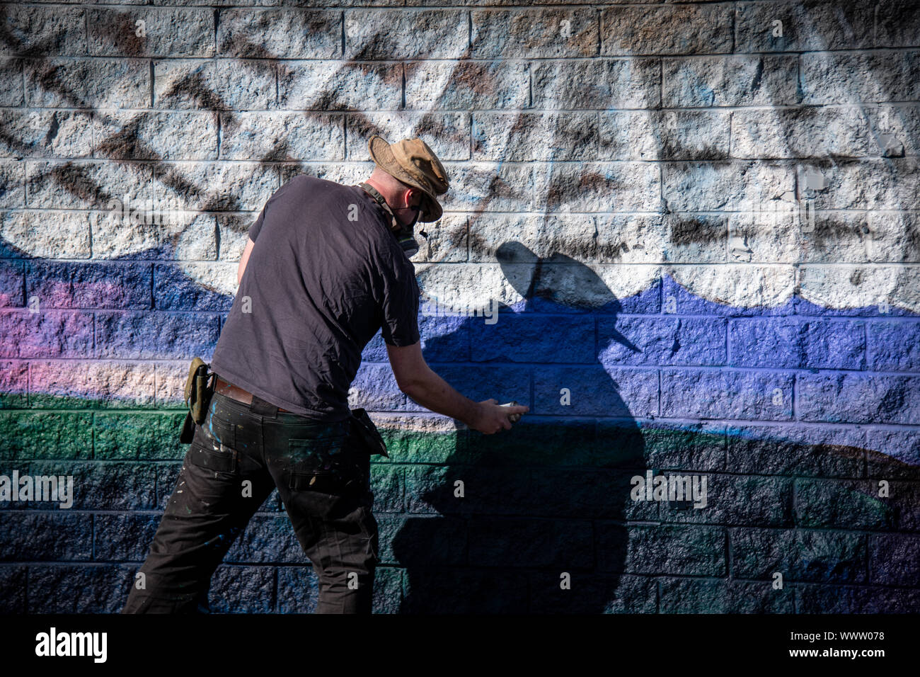 Graffiti artist painting colorful artwork with aerosol spray on the ...