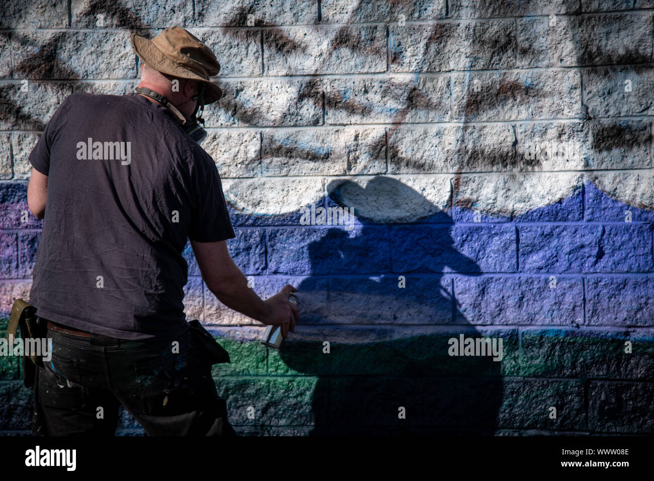 Graffiti artist painting colorful artwork with aerosol spray on the ...