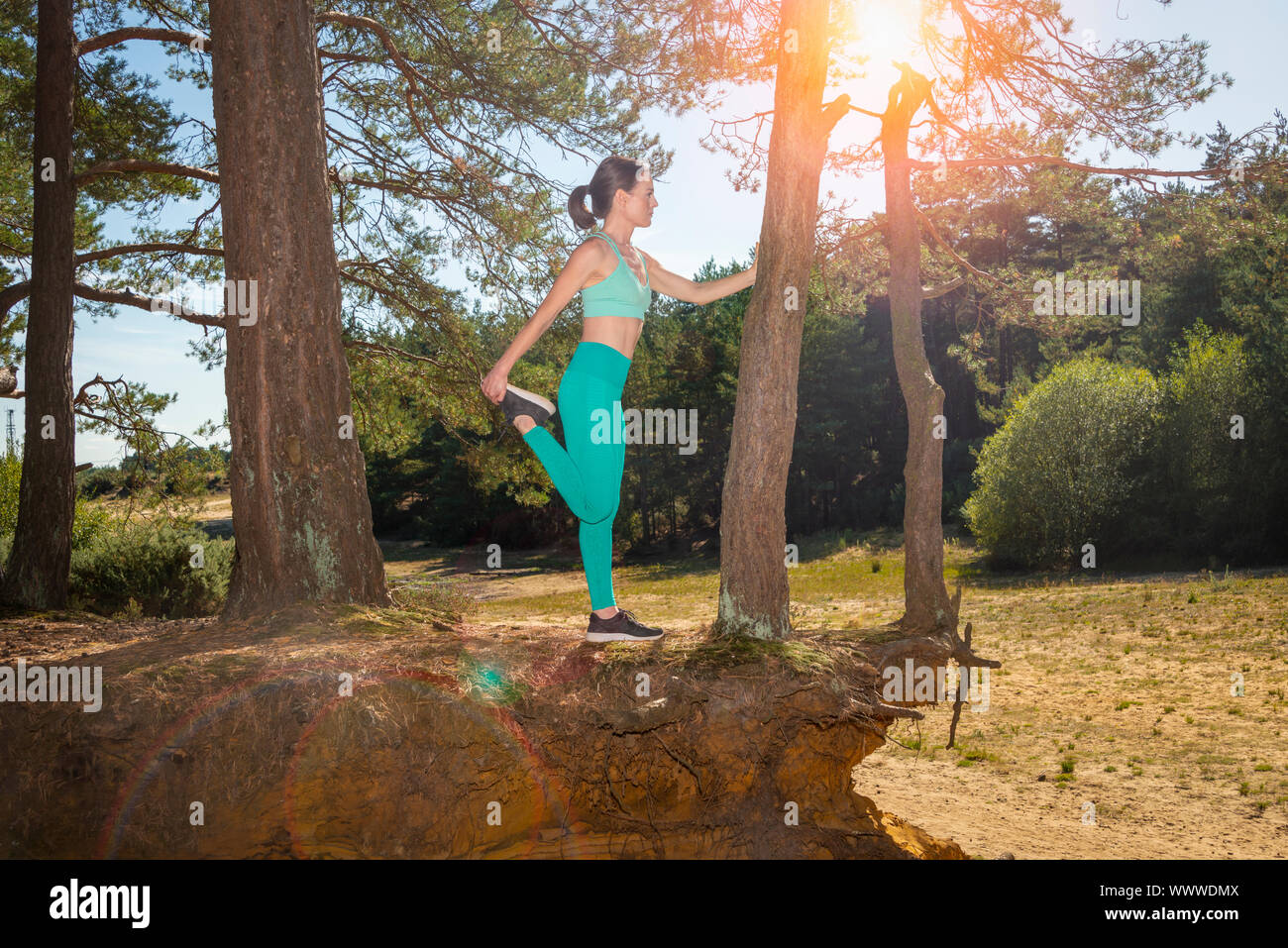 woman athlete doing a leg stretch against a tree, yoga pose. Stock Photo