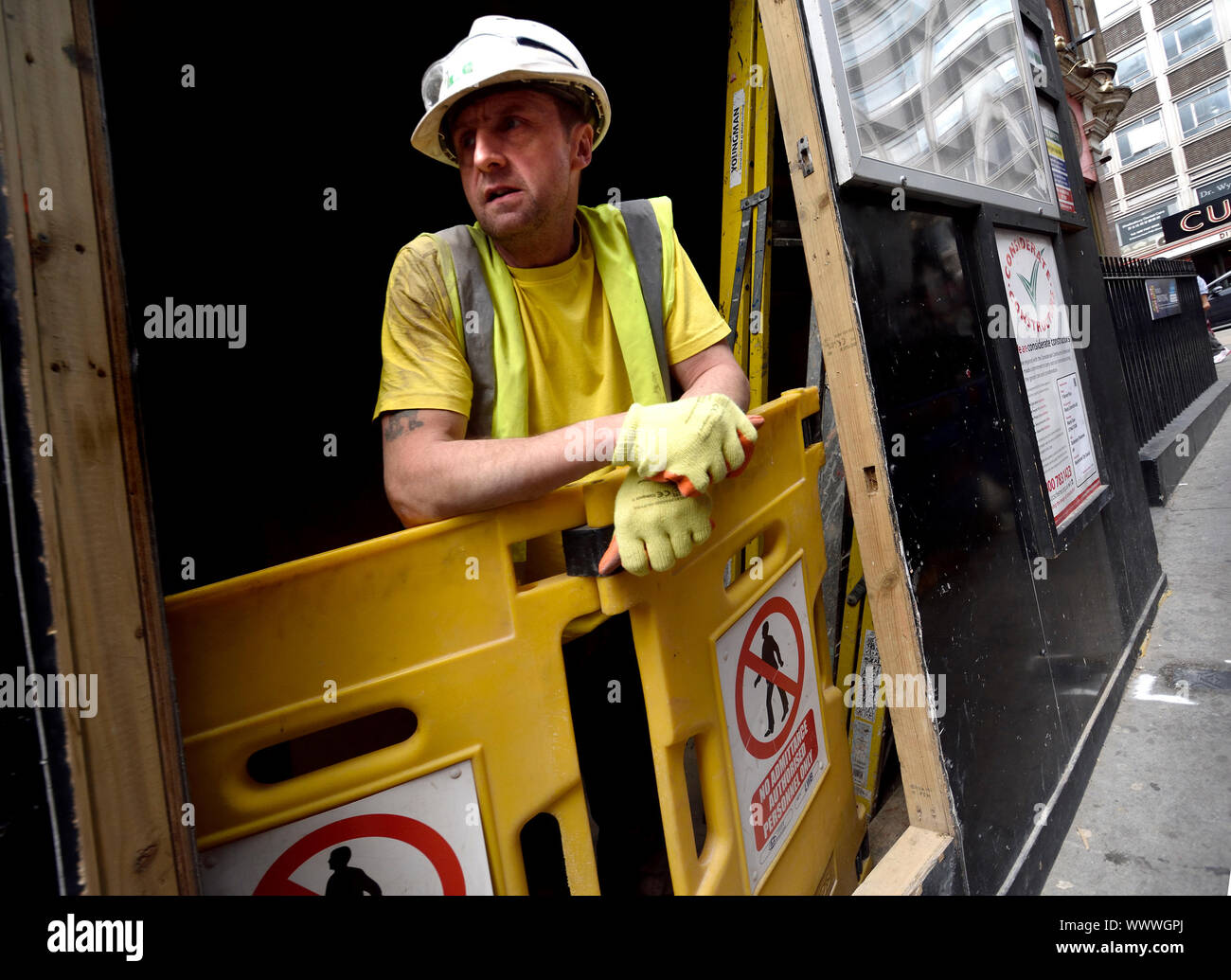 London, England, UK. Worker looking out at the street from a building site in central London Stock Photo