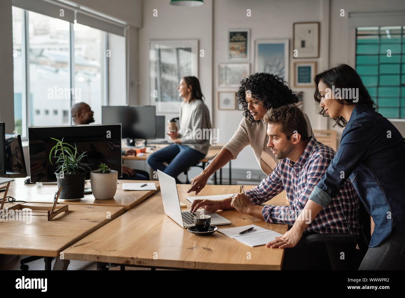 Three young designers using a laptop together at work Stock Photo