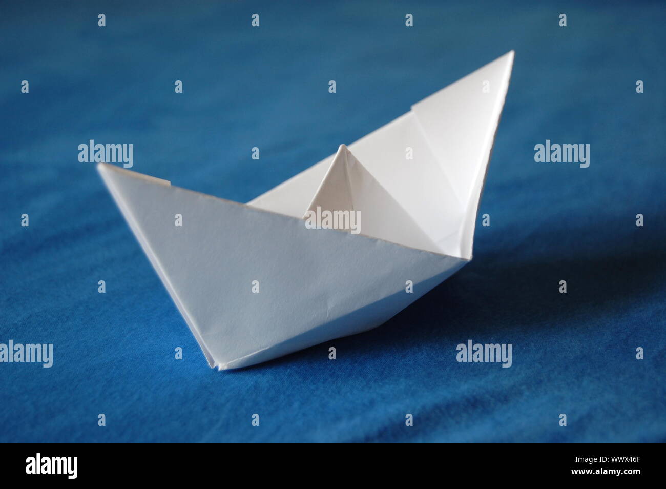 origami paper boat isolated on blue water Stock Photo - Alamy