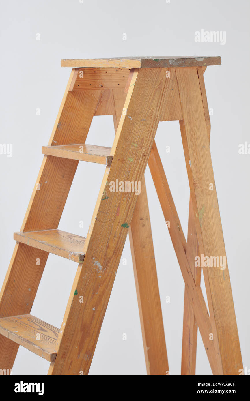 Old wooden stepladder against gray background Stock Photo