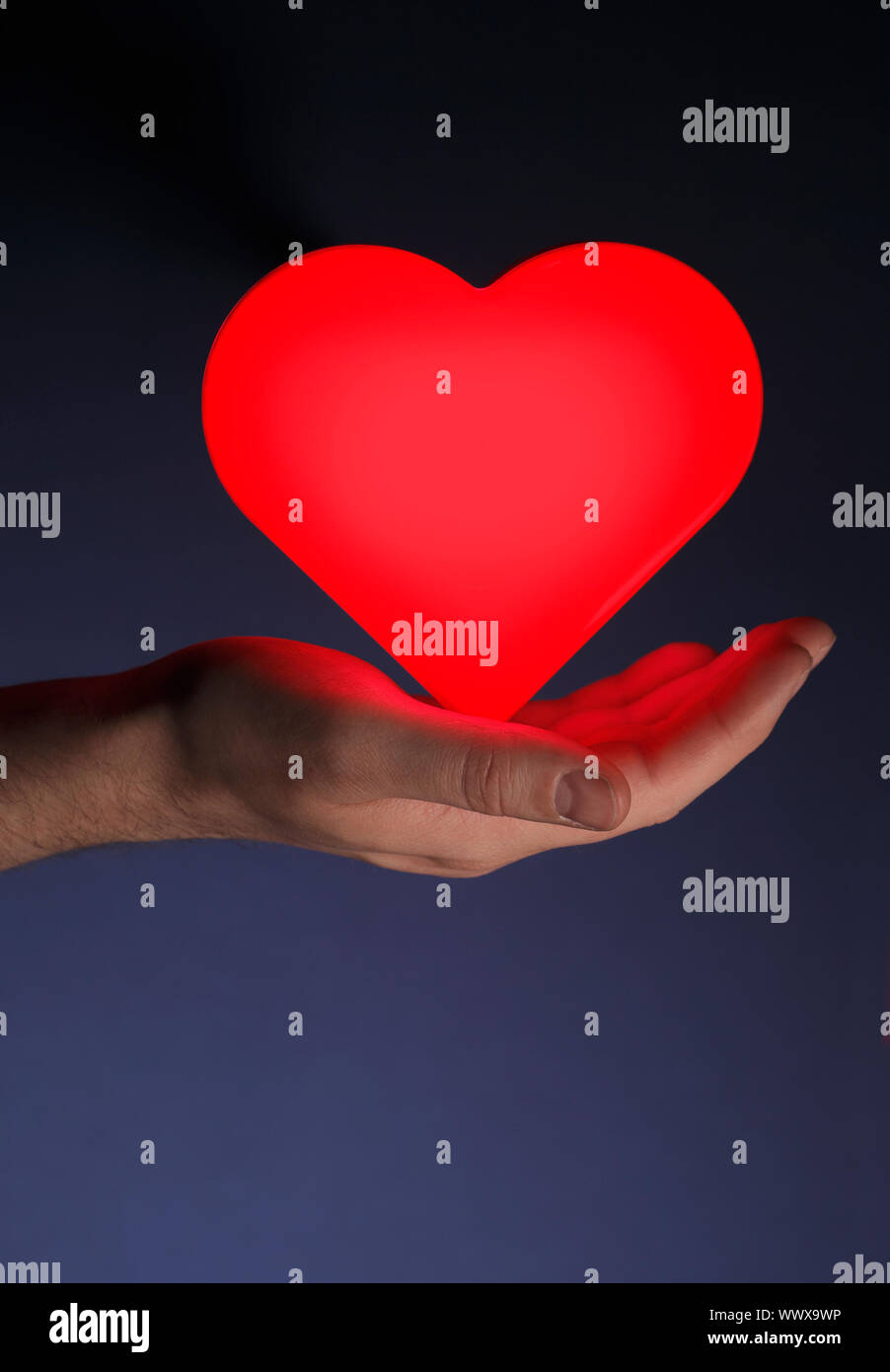 Man holding a red glowing heart shape in his hand Stock Photo - Alamy