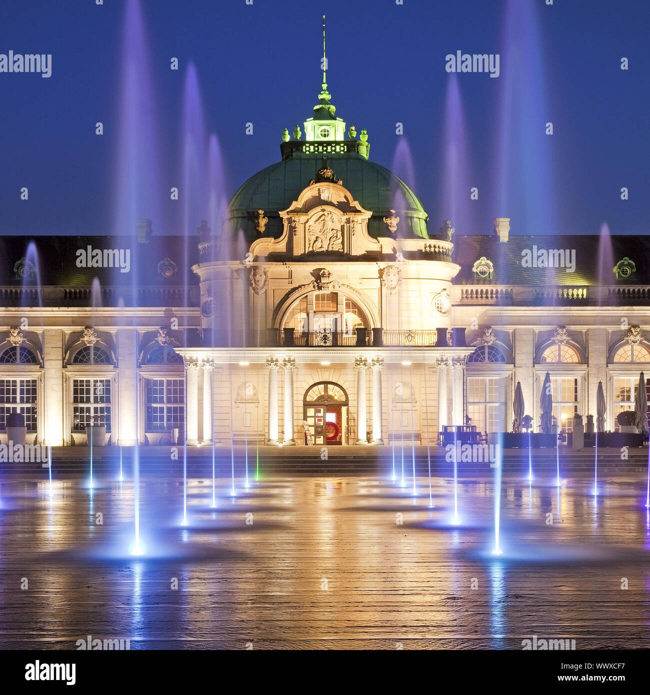 illuminated Kaiserpalais with water columns in the spa park at blue hour, Bad Oeynhausen, Germany Stock Photo